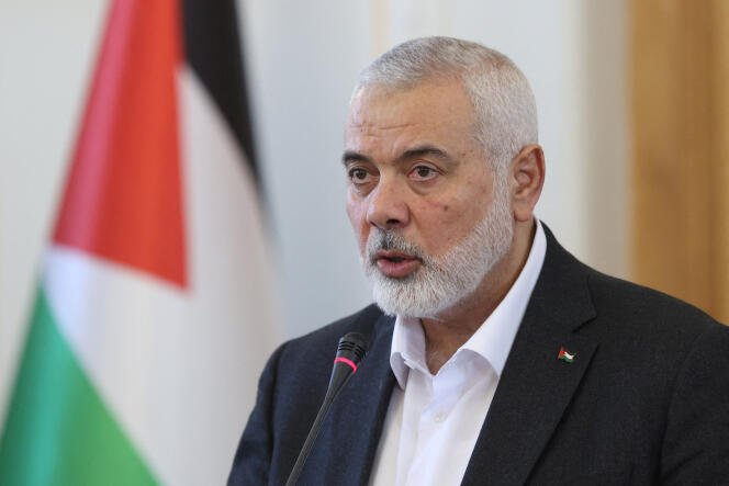 Ismail Haniyeh holds a press conference while standing on a podium with microphones and surrounded by media.