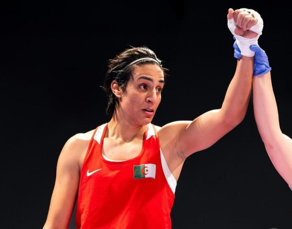 Imane Khelif celebrates her victory in a boxing battle by raising her hand.